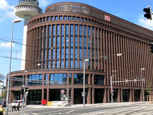 Blick auf die runde Ecke des Gebäudes mit vertikal betonter Ziegelfassade und Kreutzung im Vordergrund