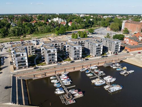 Luftbild mit Blick auf das gesamt Projekt aus vielen Gebäuden an der Marina mit Booten im Wasser