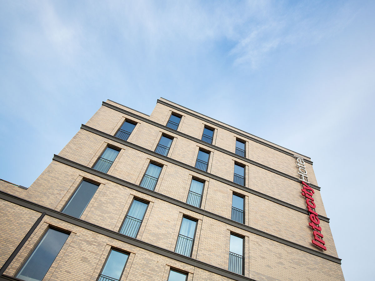 Blick von unten rauf in den Himmel, entlang der Fenster und des Logos