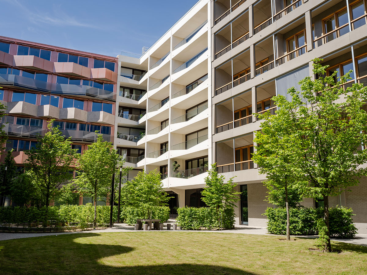 Innenhof mit Blick auf die verschiedenfarbigen Fassaden mit Balkonen und Bäumen