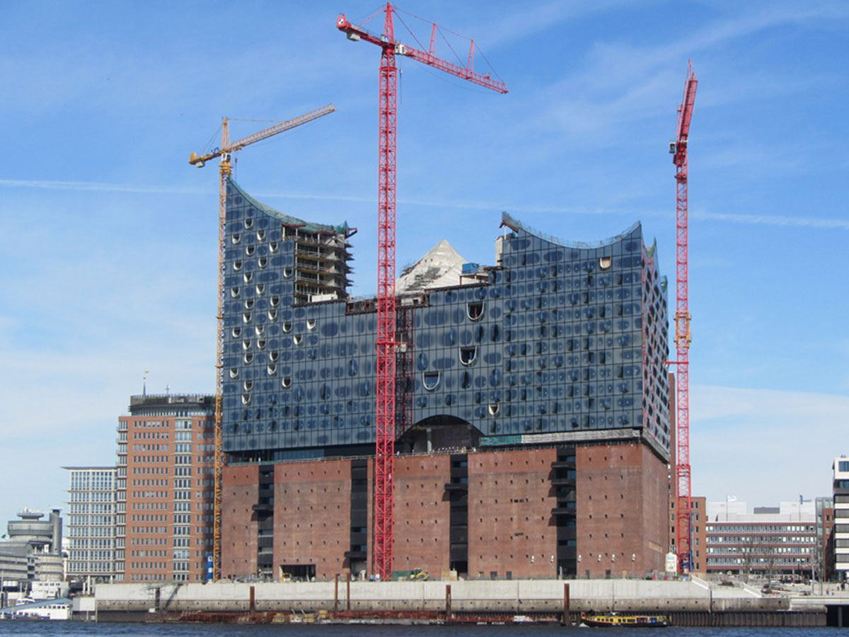 Ansicht der im Bau befindlichen Philharmonie mit Kränen an der Fassade, von der Wasserseite aus