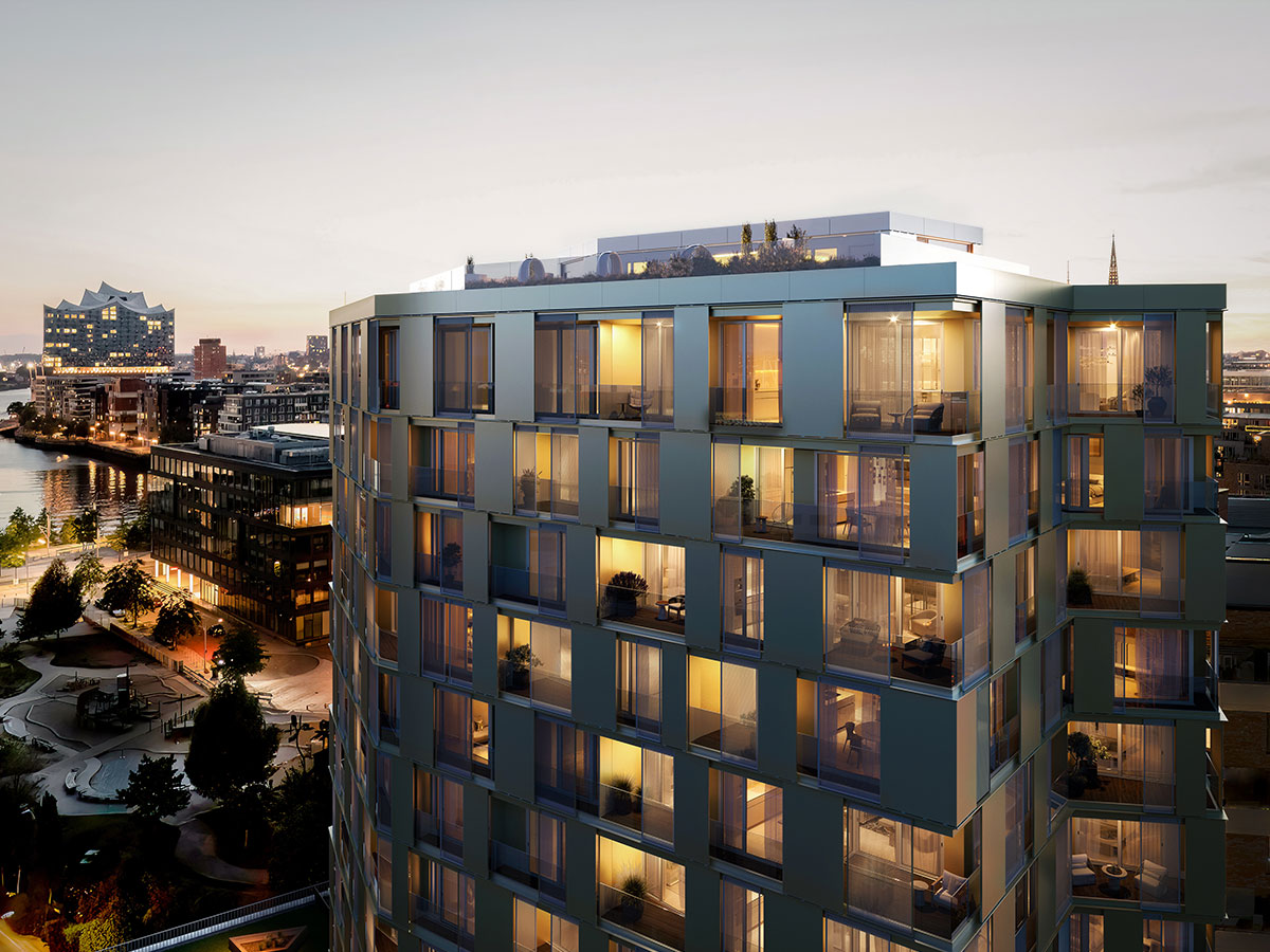 Blick auf die Hochhausfassade bei Abenddämmerung in orangem Licht mit Park und Wasserfläche im Hintergrund